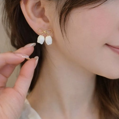 Side view of gold bow stud earrings with white pearl petal charms – casual and festive daily wear earrings for Indian women
