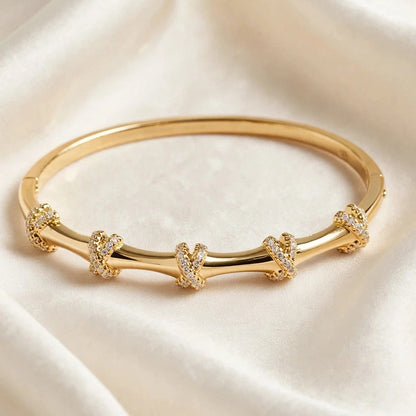 Close-up of pave crystal X knot detail on gold bangle bracelet for women at JeevaFashions