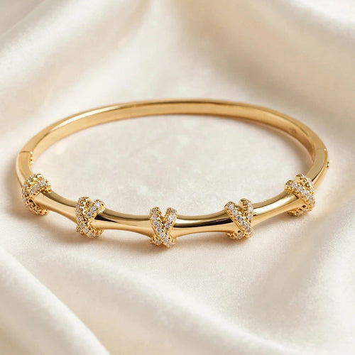 Close-up of pave crystal X knot detail on gold bangle bracelet for women at JeevaFashions