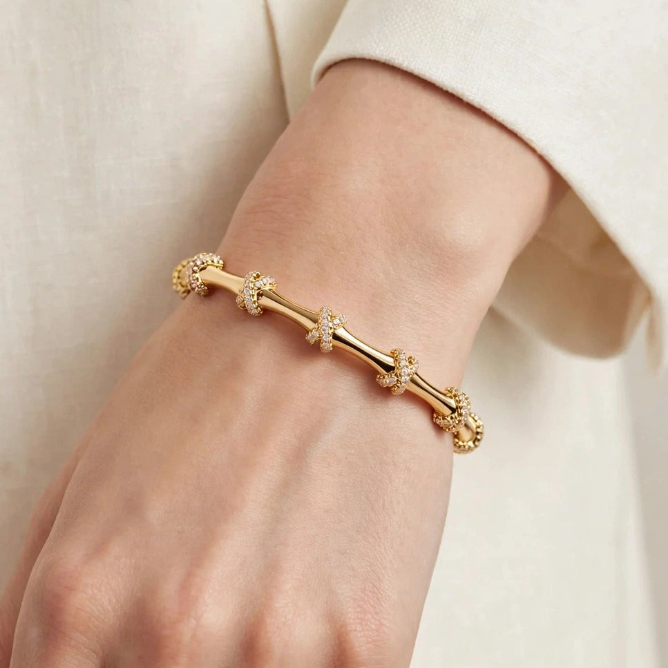 Gold pave X knot bangle bracelet displayed on jewellery box for women at JeevaFashions