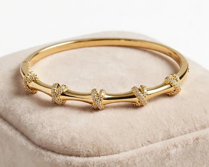 Pave X knot bangle bracelet in gold stainless steel for women at JeevaFashions