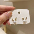 Gold plated faux pearl bunny stud earrings with crystal bow accent – flat lay on white background for women