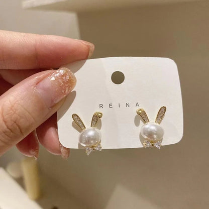 Gold plated faux pearl bunny stud earrings with crystal bow accent – flat lay on white background for women