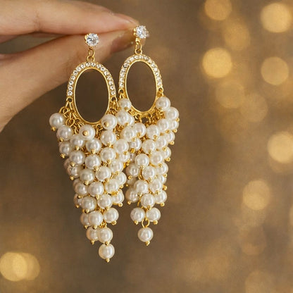 Close-up of pearl hoop earrings with cascading cluster drop and stone stud – gold tone party wear earrings for Indian women