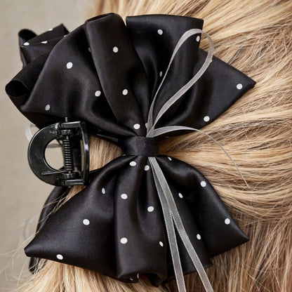 Close-up detail of black satin bow claw clip with polka dot print