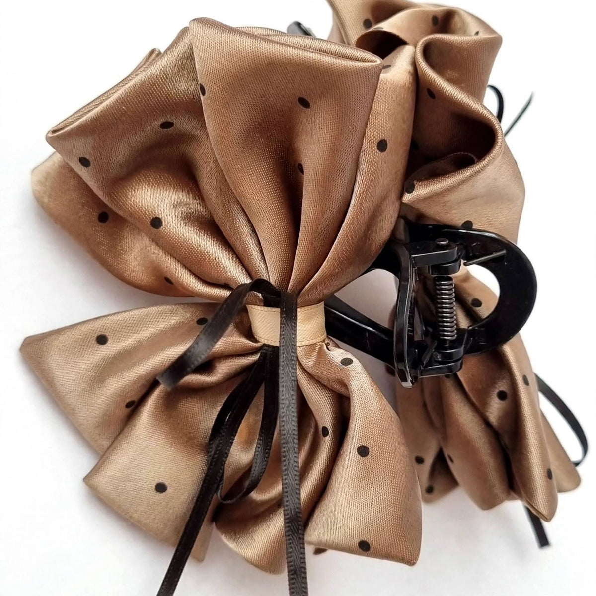 Macro close-up of brown-gold satin bow claw clip polka dot detail