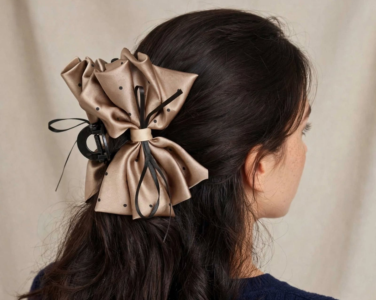 Close view of model wearing brown-gold satin polka dot bow claw clip